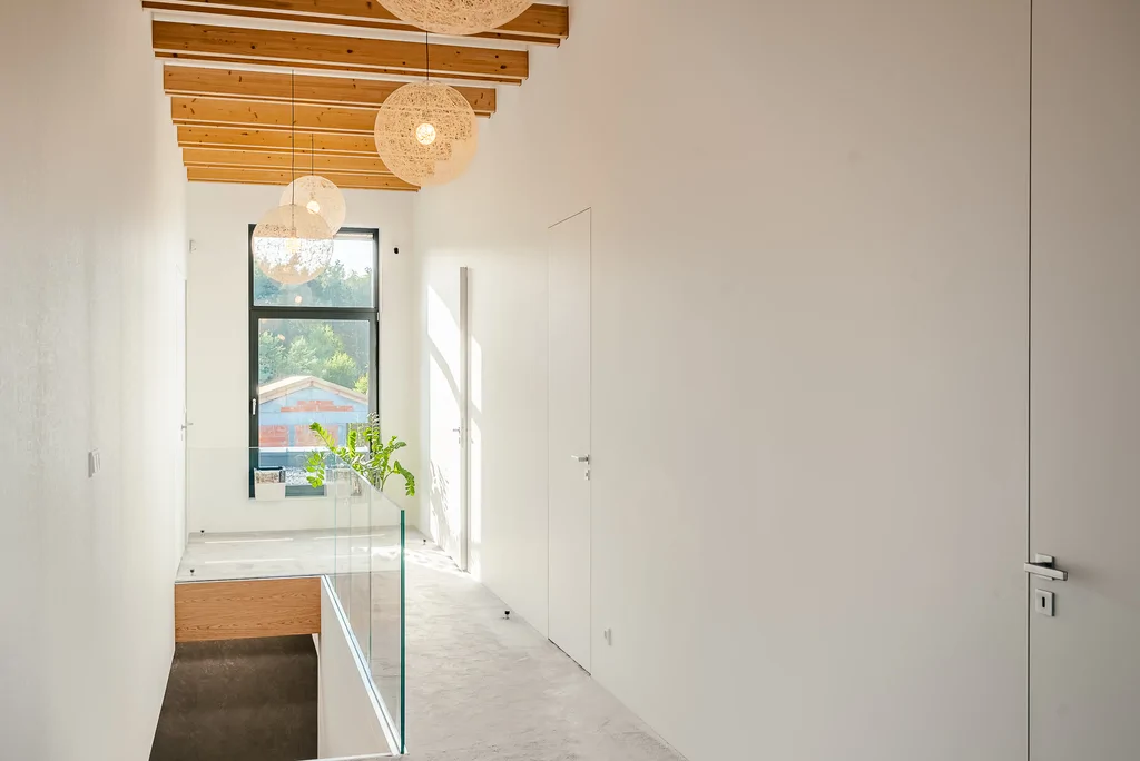 Antresola i korytarz z przeszkloną balustradą oraz dekoracyjnymi lampami kulami.