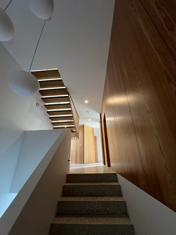 Schody wewnętrzne z drewnianymi stopniami i okładziną ścienną z drewna w nowoczesnym wnętrzu