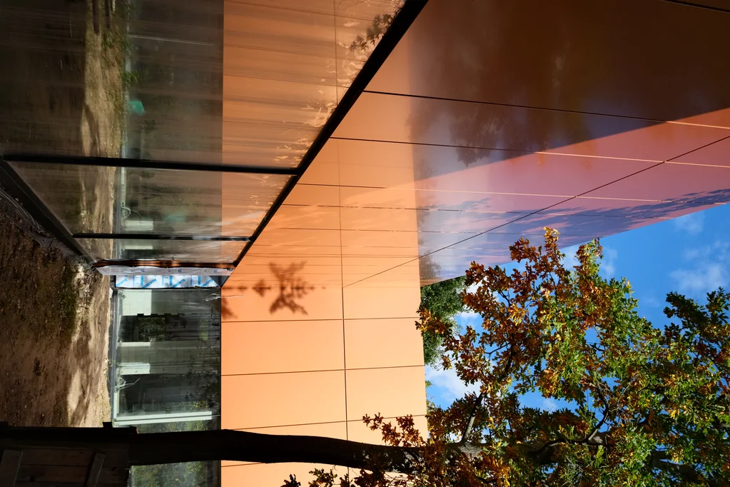 Nowoczesna elewacja z paneli w kolorze rdzawym i przeszklony narożnik budynku