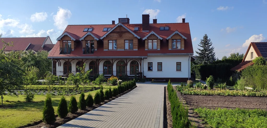 Wejście główne do domu zakonnego w Ostródzie z drewnianym zadaszeniem, schodami i balustradami