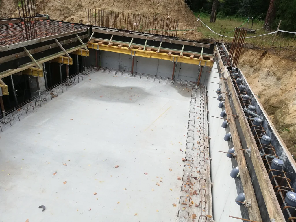 Wnętrze wykonanej piwnicy ze ścianami żelbetowymi i przygotowaniem pod dalsze prace konstrukcyjne