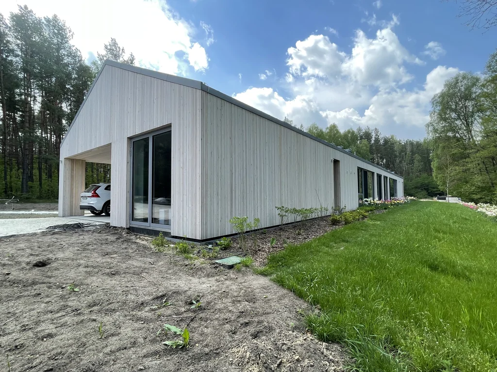 Boczne ujęcie domu z długą elewacją drewnianą i ogrodem