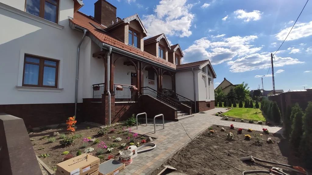 Dom zakonny w Ostródzie, widok na narożnik budynku z arkadami, czerwonym dachem i chodnikiem z kostki brukowej