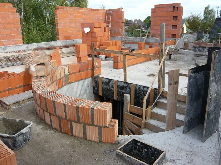 murowana ściana łukowa przy otworze klatki schodowej, tymczasowe schody na budowie