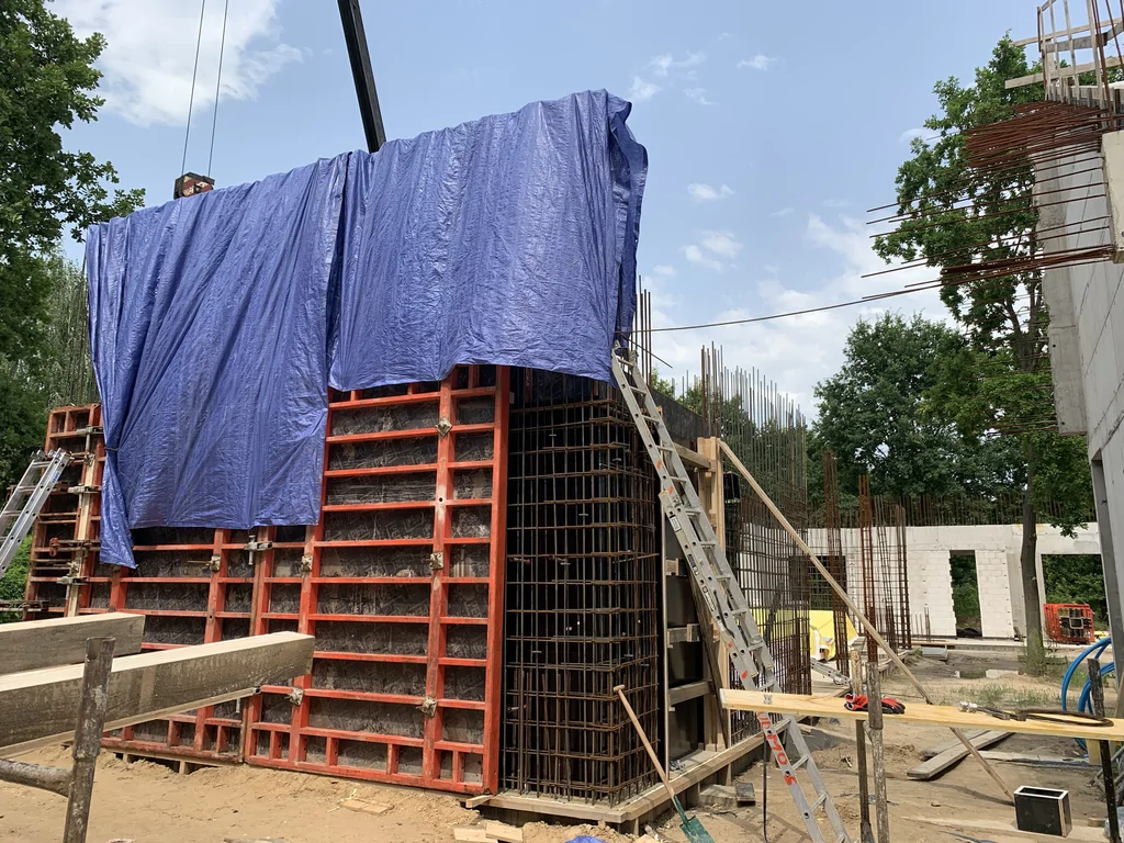 Szalunek ściany żelbetowej (zabezpieczony plandeką) i zbrojenie naroża – przygotowanie betonu architektonicznego