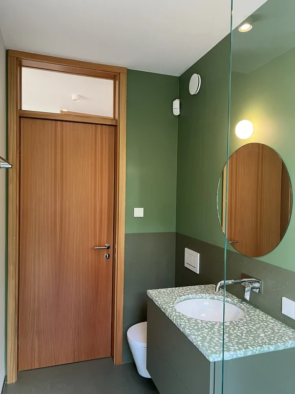 Pokój z dużym przeszkleniem i wyjściem na drewniany taras z widokiem na drzewa