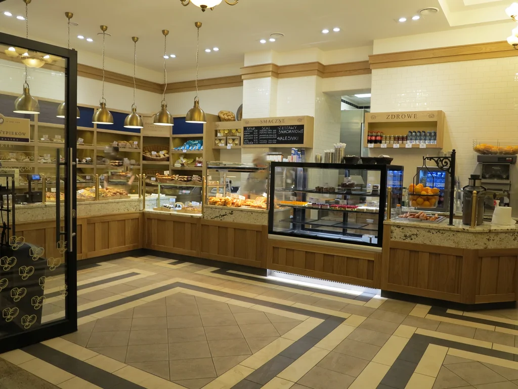 Zdjęcie piekarni w wewnątrz, w tle kasa i półki z pieczywem