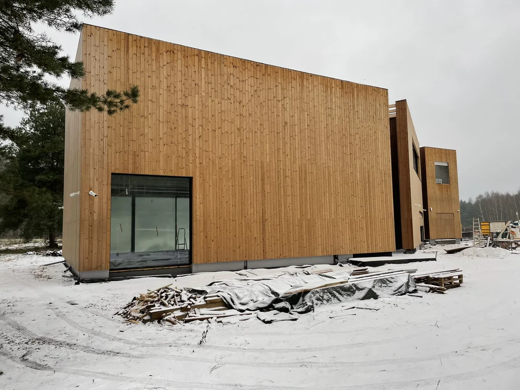 Elewacja z pionowym deskowaniem i dużym przeszkleniem; ujęcie w warunkach zimowych.