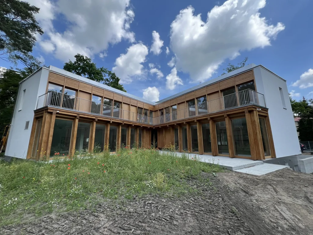 Nowoczesny dom z drewnianą elewacją i dużymi przeszkleniami wokół wewnętrznego dziedzińca