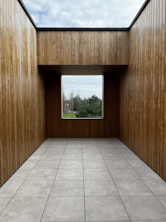 Widok z antresoli na przestrzeń schodów; długi pas okna, minimalistyczne sufity liniowe i dębowa podłoga.