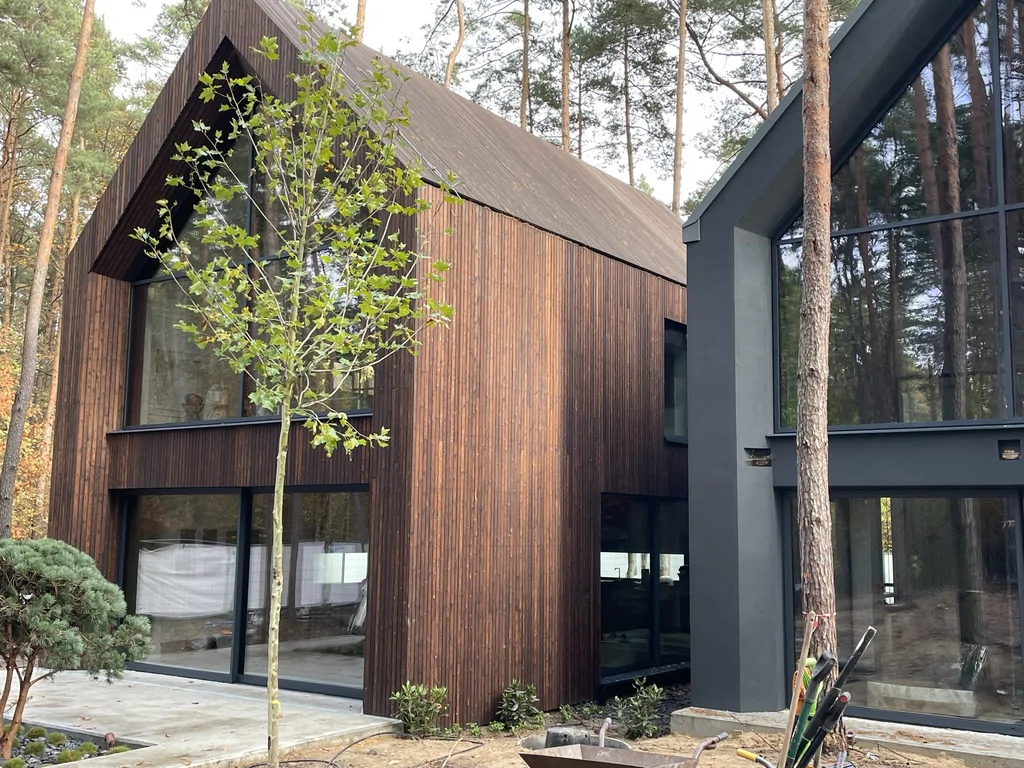 Nowoczesny dom w lesie w Magdalence z dwiema bryłami, drewnianą elewacją i dużymi przeszkleniami