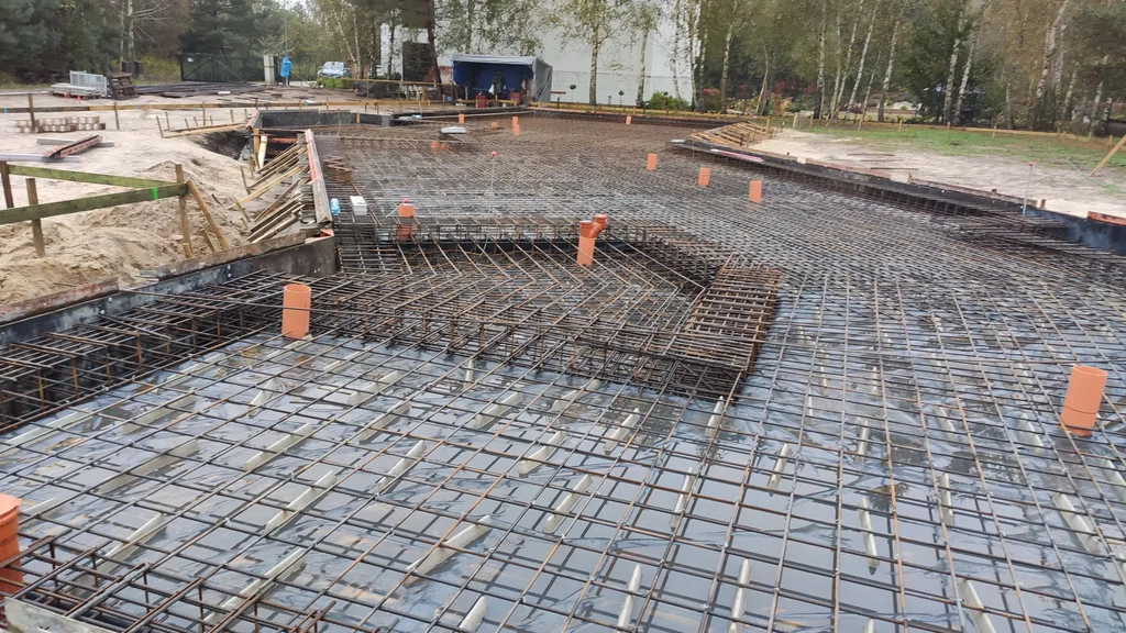 Zbrojenie płyty fundamentowej – siatki stalowe i przepusty pod instalacje przygotowane przed betonowaniem.