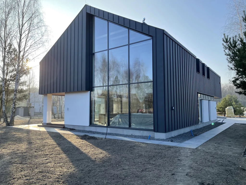 Nowoczesny dom z panoramicznym przeszkleniem szczytowym, elewacja w czarnej blasze