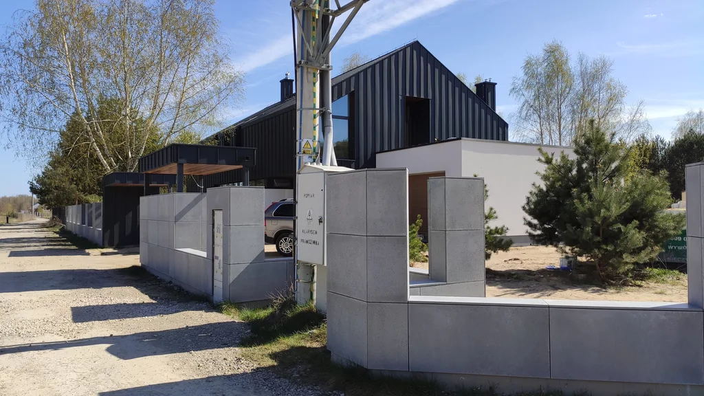 Nowoczesny dom za betonowym ogrodzeniem, widok od strony drogi i bramy wjazdowej