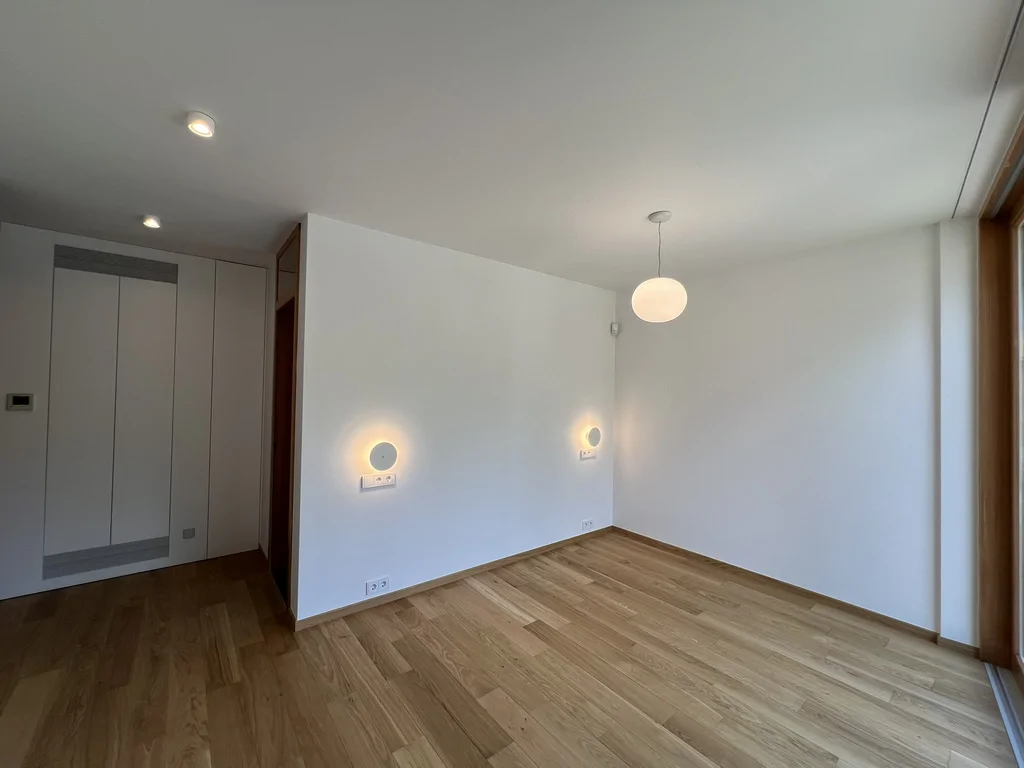 Pokój z dużym oknem tarasowym, drewnianą podłogą i kulistą lampą wiszącą