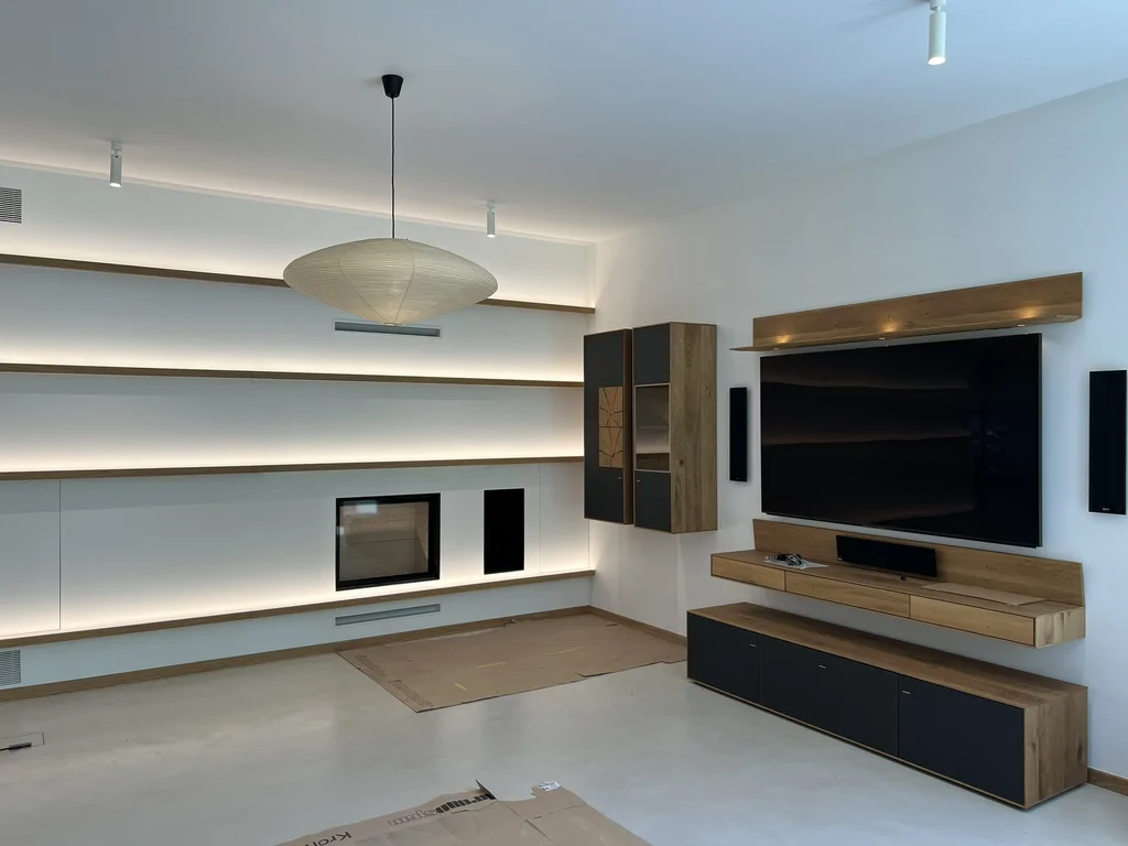 Salon z podświetlaną ścianą, kominkiem i zabudową RTV w nowoczesnym domu