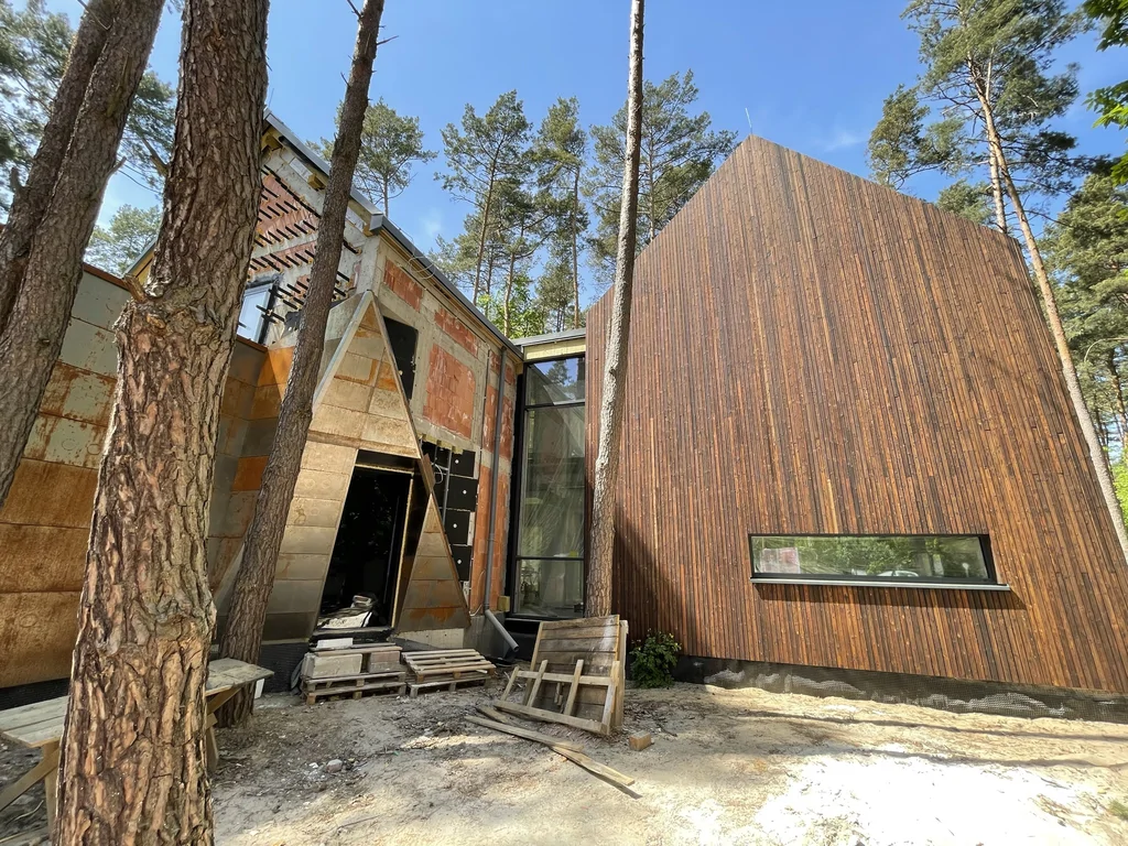 Wejście do nowoczesnego domu w Magdalence z drewnianą elewacją, przeszkleniem łącznika i stalową okładziną