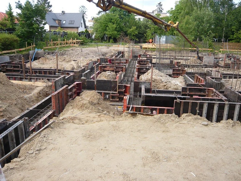 szalunki i zbrojenie ław, widoczny wysięgnik pompy do betonu