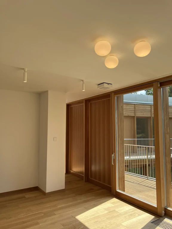 Pokój z panoramicznymi oknami, drewnianą podłogą i nagłośnieniem sufitowym