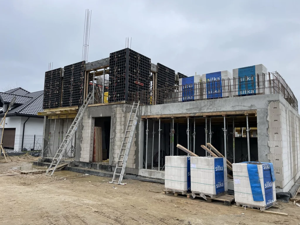 Stan surowy budynku z żelbetową konstrukcją, murowanymi ścianami z silikatów oraz deskowaniem górnej kondygnacji