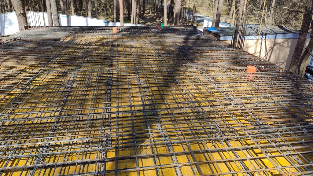 Zbrojenie płyty żelbetowej i deskowanie otworu technologicznego podczas budowy domu na studniach