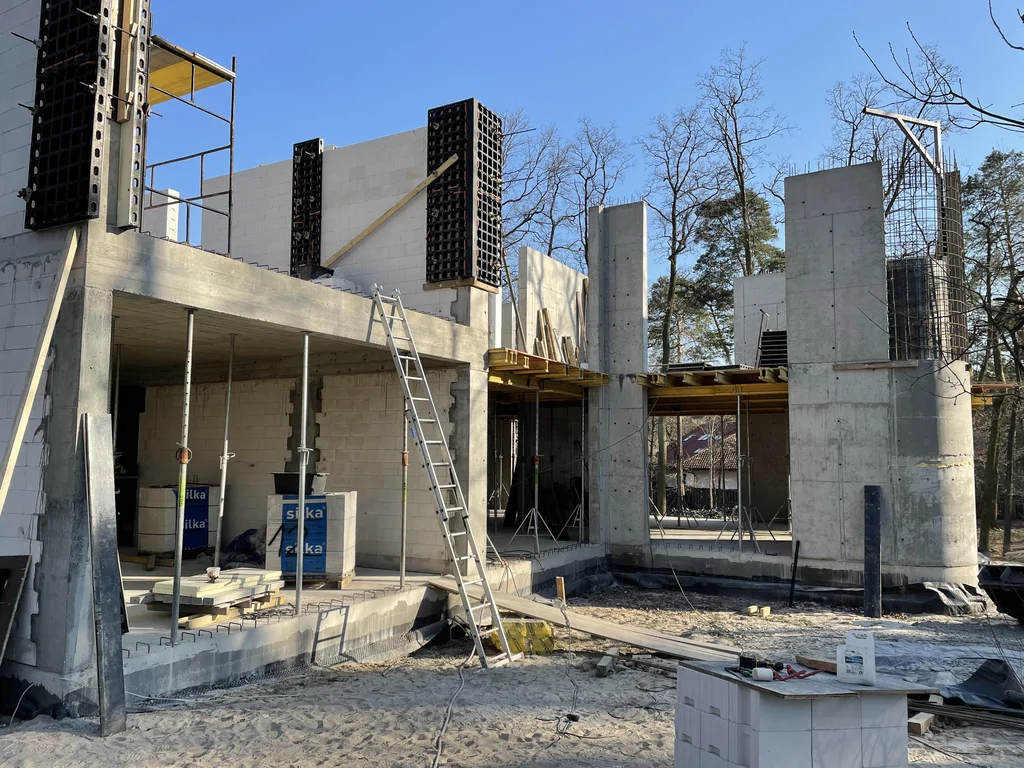 Detal stanu surowego domu z żelbetową konstrukcją, murowanymi ścianami i strefą wewnętrznego dziedzińca