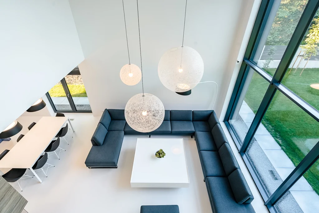 Widok z góry na salon z narożną sofą i trzema dużymi lampami wiszącymi.