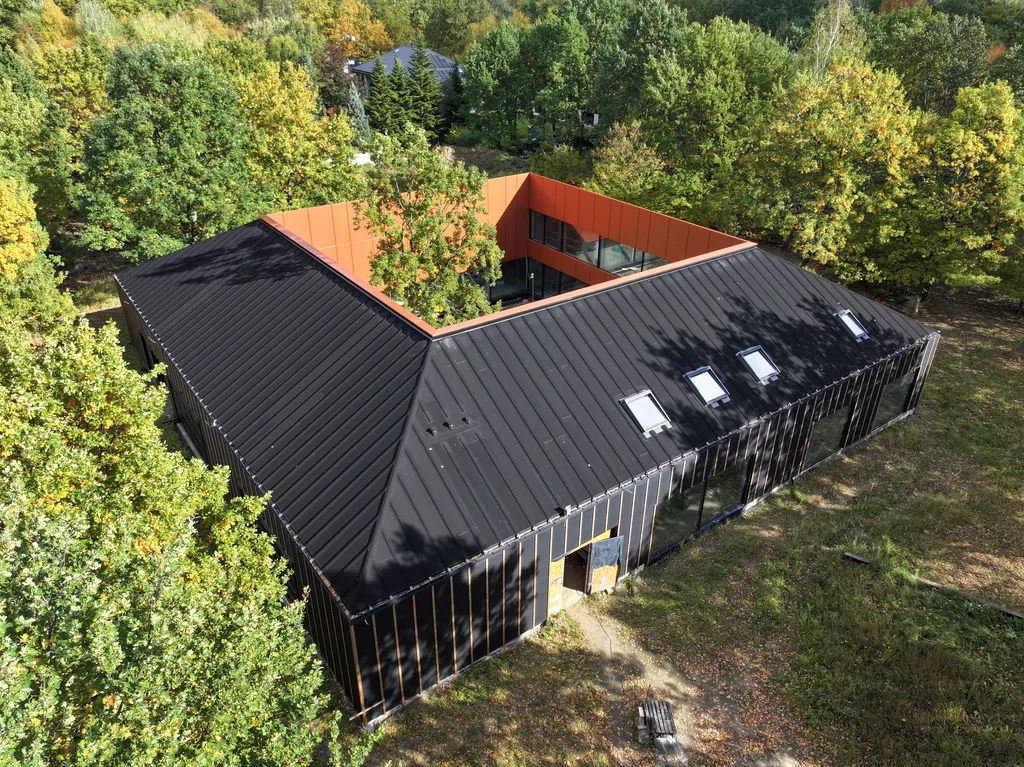 Widok z lotu ptaka na dom z czarnym dachem i cortenową elewacją