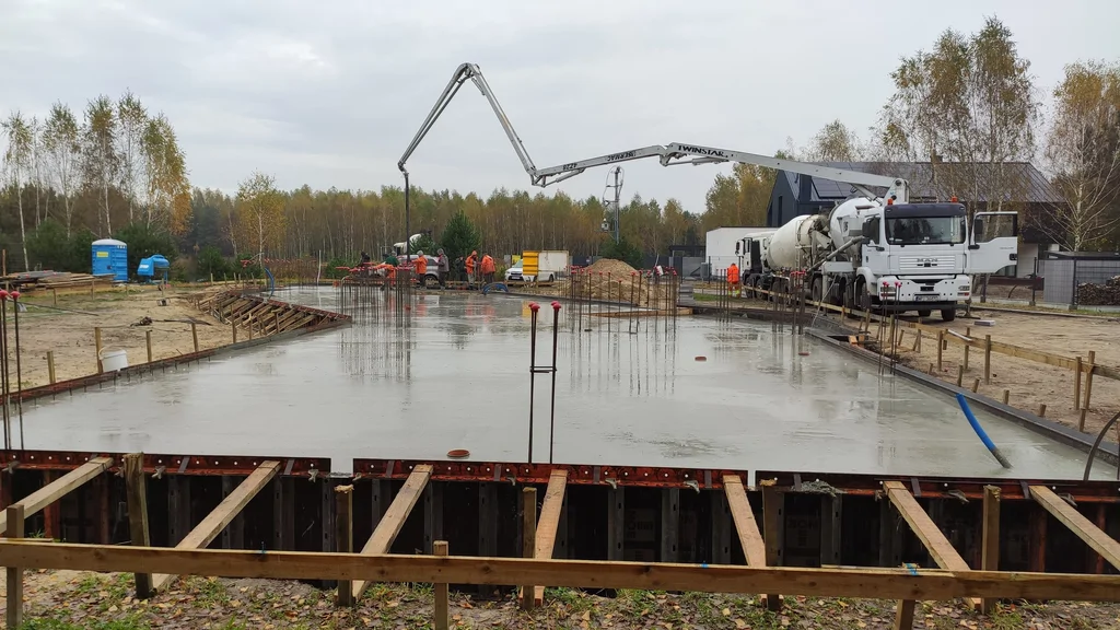 Betonowanie płyty fundamentowej z użyciem pompy – prace w trakcie wylewania i zacierania.