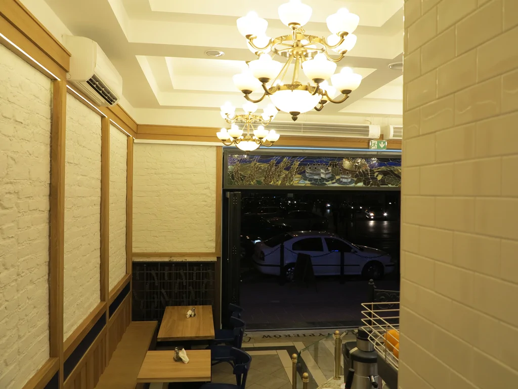 zdjęcie piekarni wewnątrz, stoliki, posadzka z podświetlanymi otworami, na ścianach kamień i drewno 