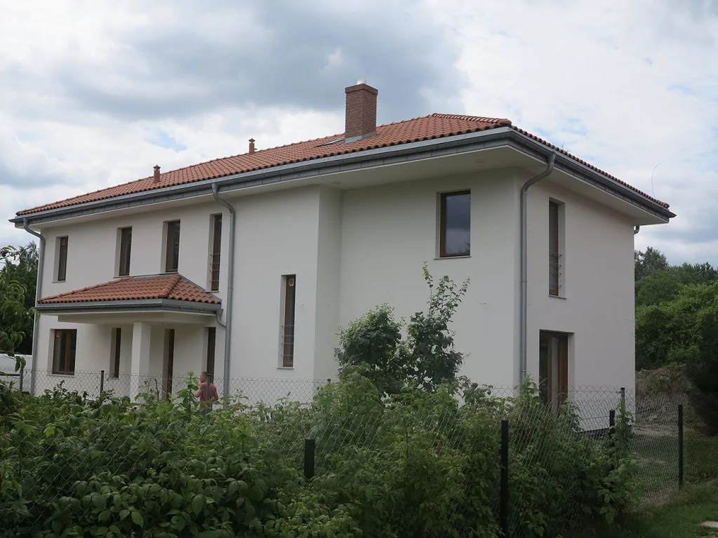 Budowa domu jednorodzinnego, widok z zewnątrz na wykonaną elewację, ciemna stolarka okienna, gotowe pokrycie dachowe