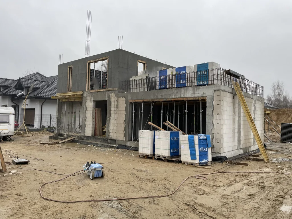 Zaawansowany stan surowy domu z wykonanymi ścianami żelbetowymi, stropem i przygotowaniem do kolejnych etapów robót