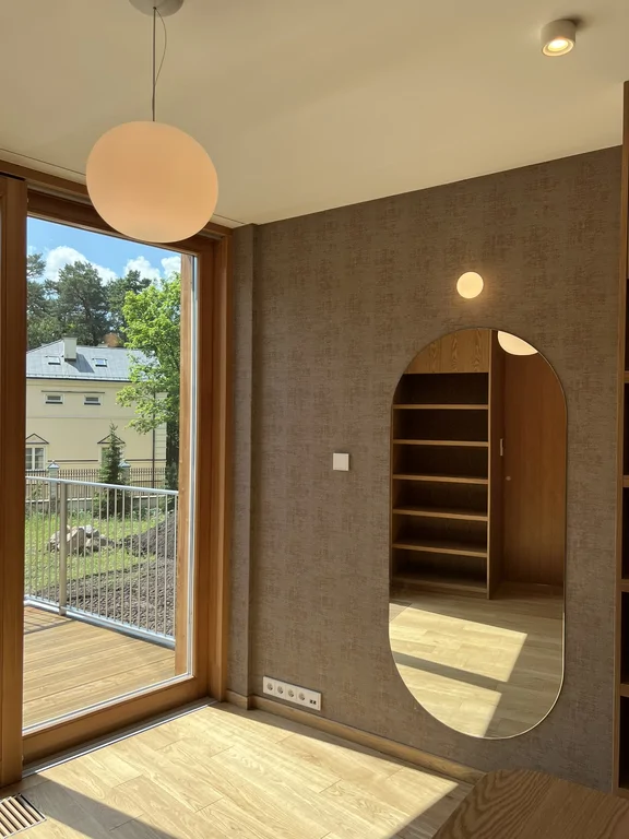 Pokój z dużym przeszkleniem, drewnianą podłogą i nowoczesnym oświetleniem sufitowym