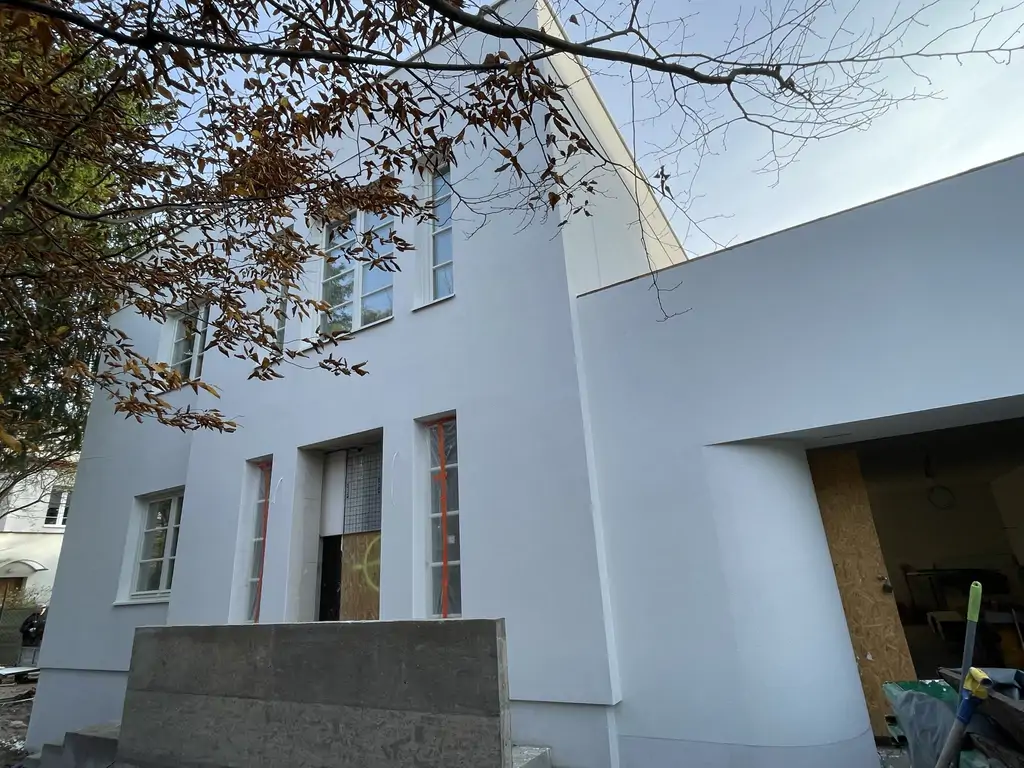 Odnowiona elewacja budynku po remoncie zewnętrznym – widok od strony wejścia i garażu.