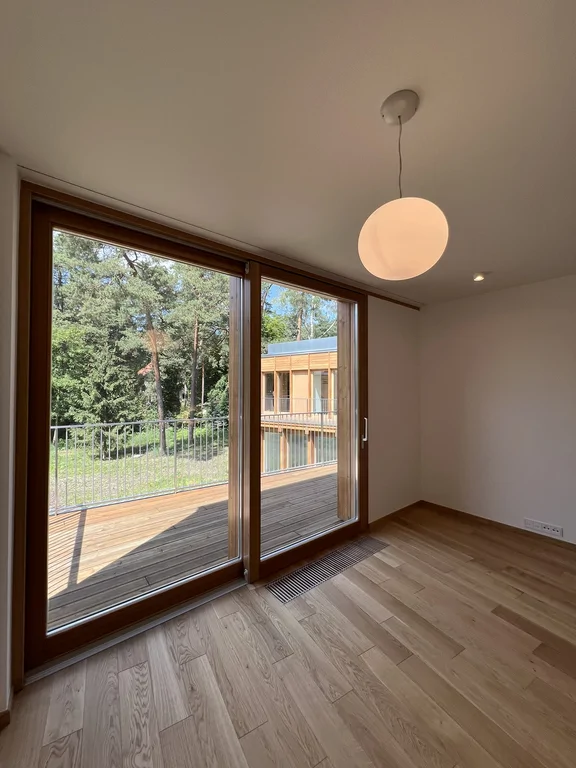 Pokój z dużym oknem tarasowym, drewnianą podłogą i kulistą lampą wiszącą