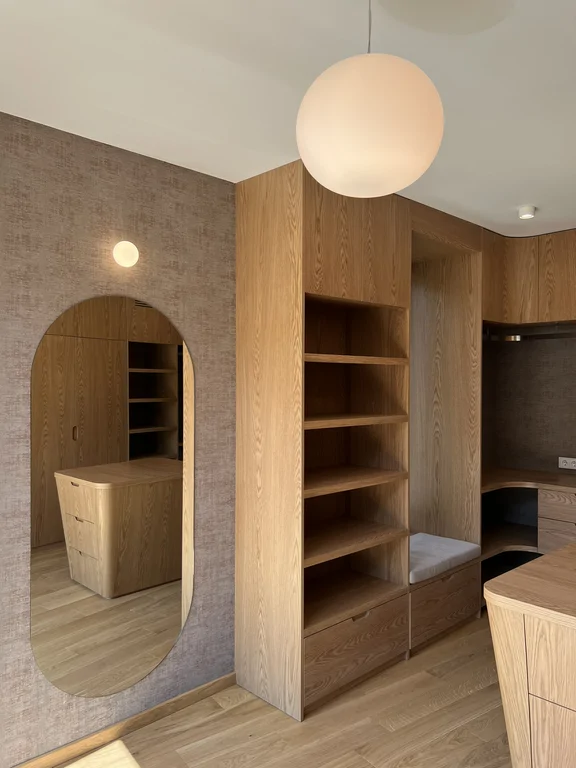 Garderoba z drewnianą zabudową, lustrem i wyjściem na balkon