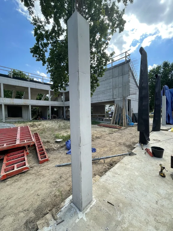 Słup z betonu architektonicznego na tle konstrukcji parteru i piętra – żelbet w stanie surowym