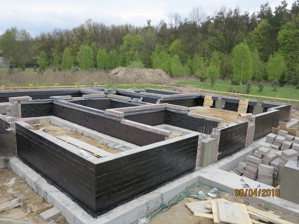 ławy fundamentowe, wykonane ściany fundamentowe z bloczka pokryte szlamem, częściowo wylane słupy 