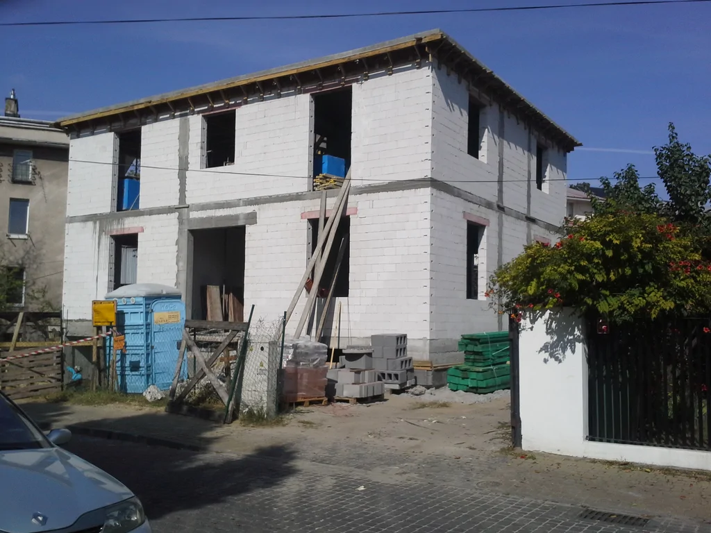 Budowa domu jednorodzinnego, stan surowy, widok z zewnątrz na mury i elementy żelbetowe