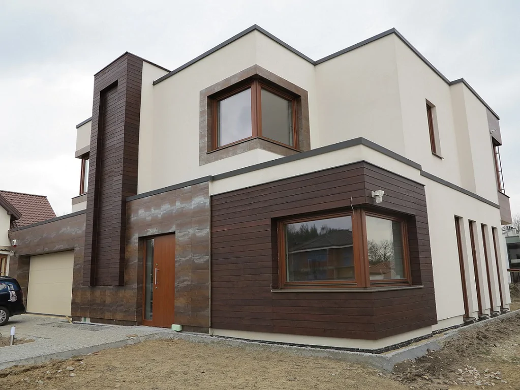 Nowoczesny dom z dachem płaskim: jasny tynk, duże okna i okładzina elewacyjna