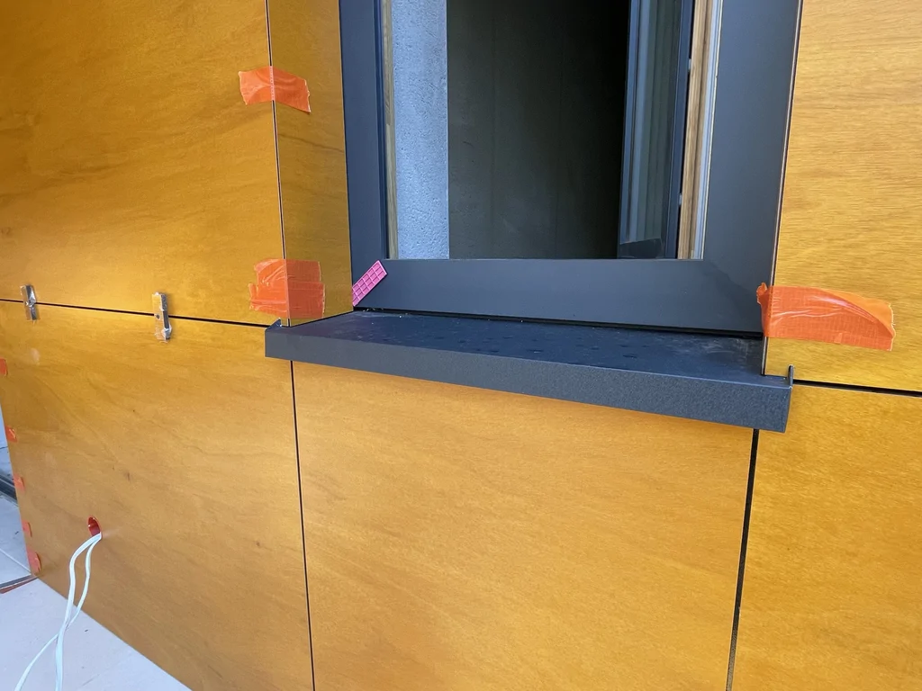 Detal elewacji nowoczesnego domu w Podkowie Leśnej z oknem, parapetem antracytowym i okładziną w kolorze drewna