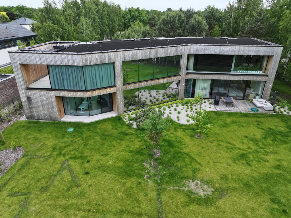 Dom Prawdziwka – panoramiczny widok na elewację od ogrodu, długie przeszklenia i taras.