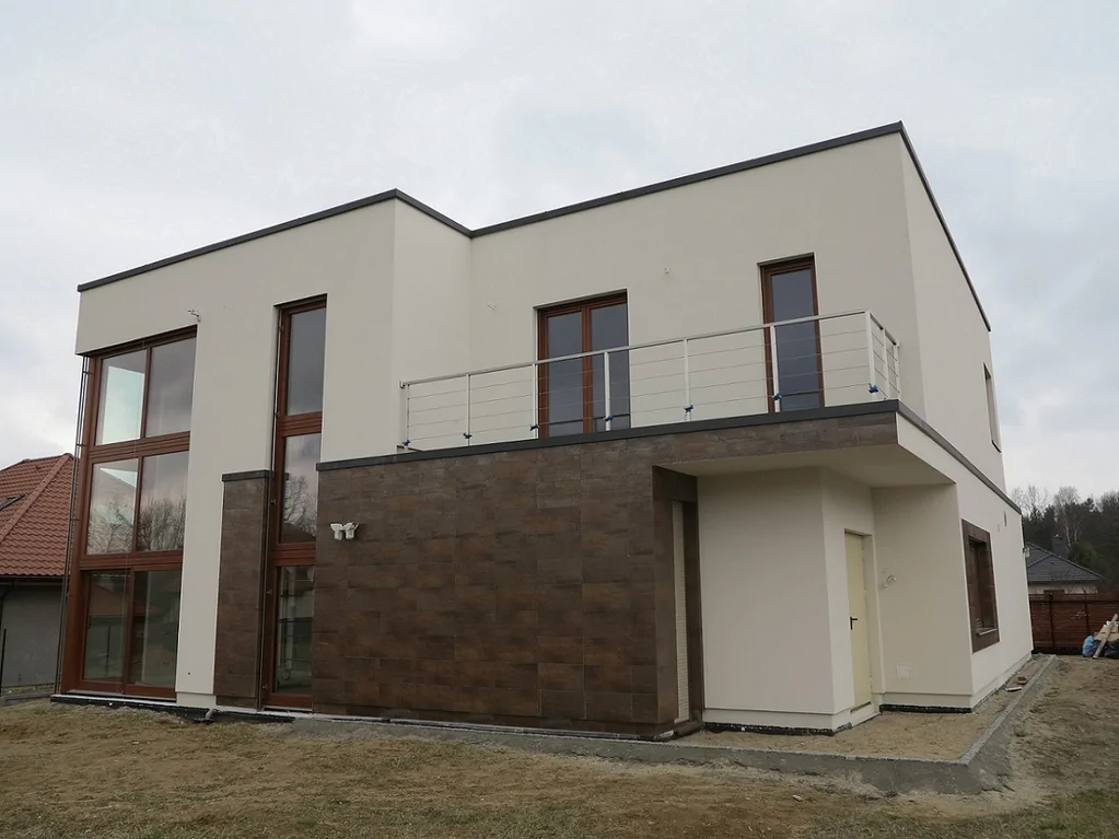 Elewacja z balkonem i metalową balustradą – zestawienie tynku z okładziną elewacyjną