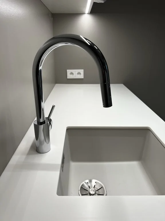 Zbliżenie na zlew podwieszany i baterię w czerni/chromie. Czysta geometria i prosta linia blatu.
