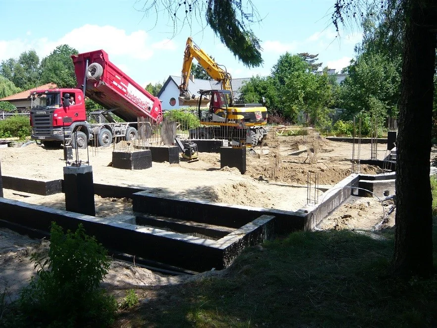 prace ziemne przy fundamentach: koparka i wywrotka podczas zasypek/niwelacji terenu