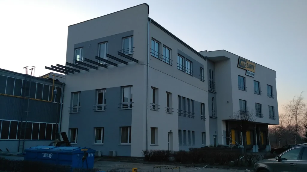 Widok na nadbudowany budynek z zewnątrz z wystawionymi belkami pod taras