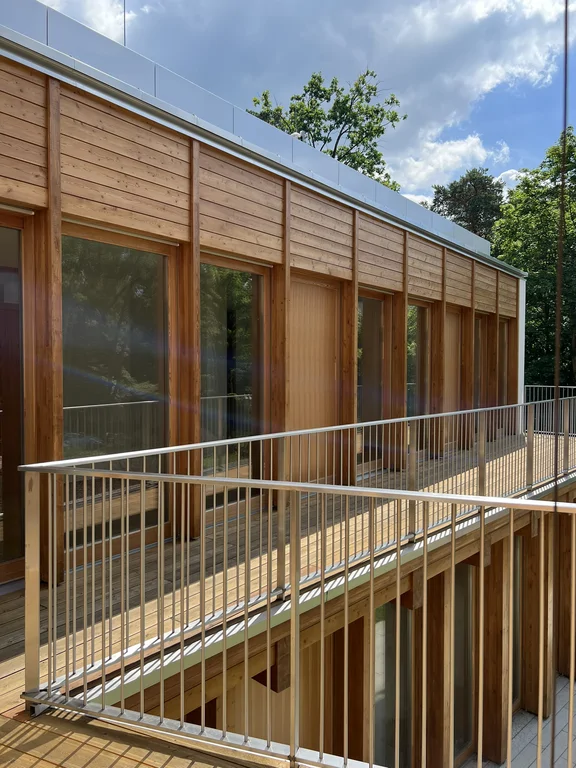 Elewacja od strony dziedzińca z drewnianym wykończeniem, dużymi oknami i balkonem