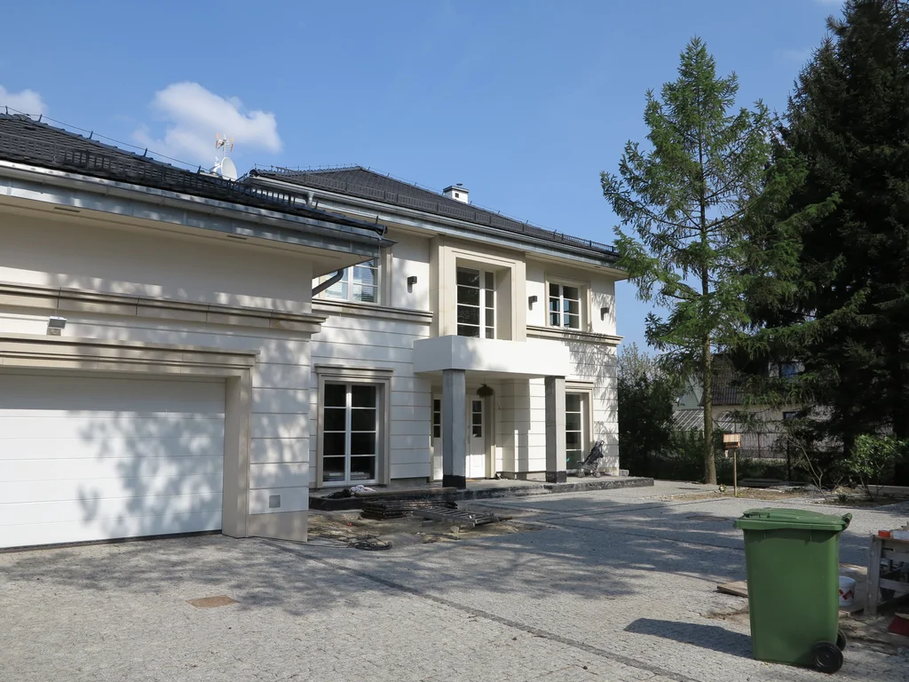 widok z podjazdu na garaż i zadaszone wejście do domu w stanie deweloperskim