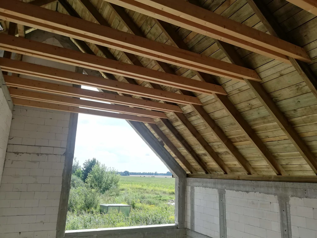 Więźba dachowa od wewnątrz – krokwie i poszycie w strefie szczytu z dużym otworem okiennym