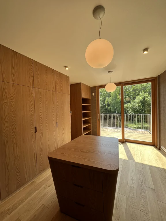 Lustro w garderobie przy dużym oknie balkonowym i drewnianej zabudowie